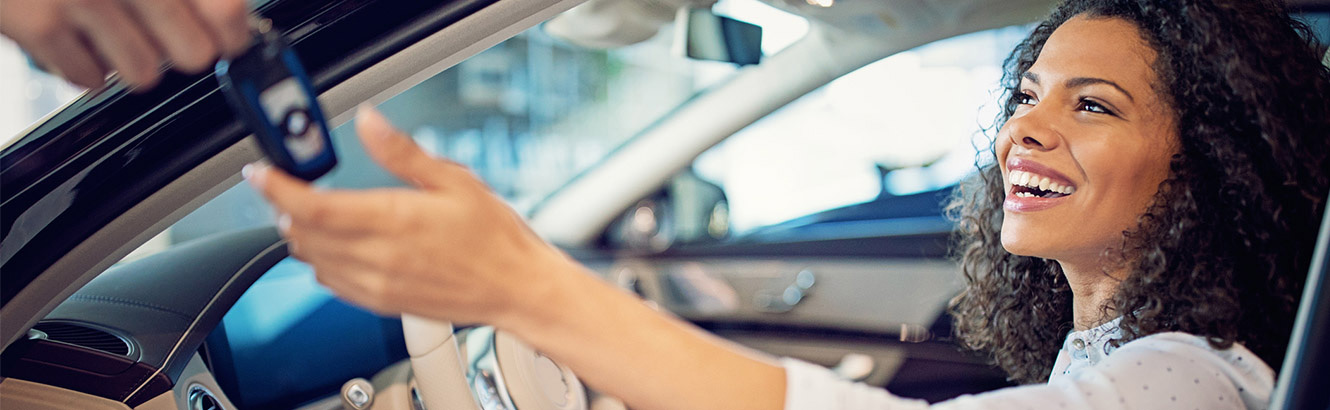 Young woman taking possession of the keys to her new car.